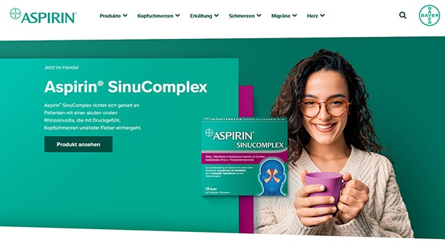 Werbung für Aspirin SinuComplex mit einer Person, die eine Tasse hält. Produktverpackung mit deutschem Text.