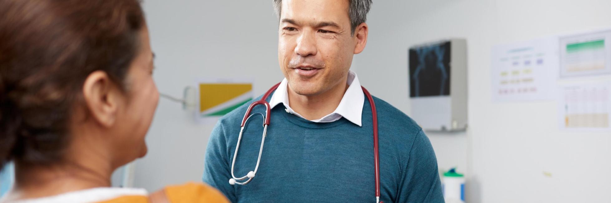 Arzt mit Stethoskop im Gespräch mit einem Patienten in einer Arztpraxis.