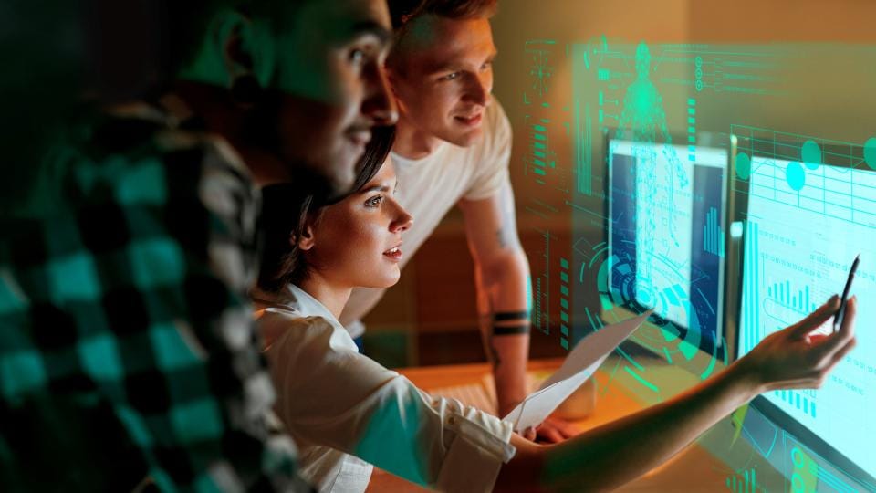 Gruppe junger Personen schauen auf Monitor 